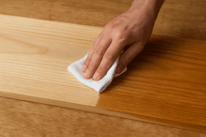 White cloth wiping down a wood board with mineral spirits
