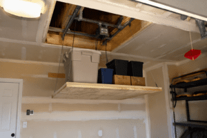 DIY attic lift platform made from plywood lifting storage bins into a garage attic using a hoist system