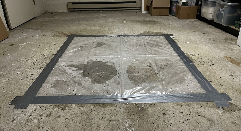 Plastic sheet taped to basement concrete floor for moisture test with sealed edges