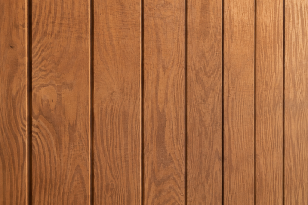 Close-up of stained T1-11 plywood siding showing vertical grooves and wood grain