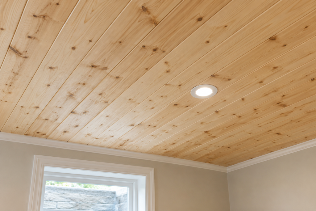 Close view of a pine tongue-and-groove basement ceiling with visible plank seams and wood grain